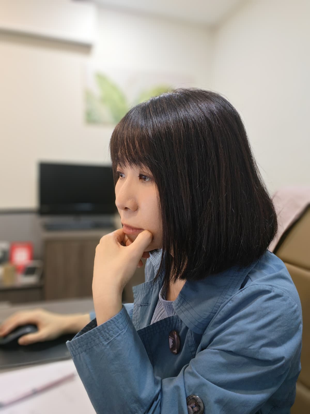 Piano Lam 林少琴坐在工作桌前，一手托着下巴，另一手放在滑鼠上